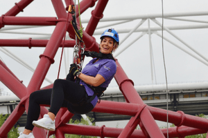 A woman looks excited as she is suspended by climbing gear.